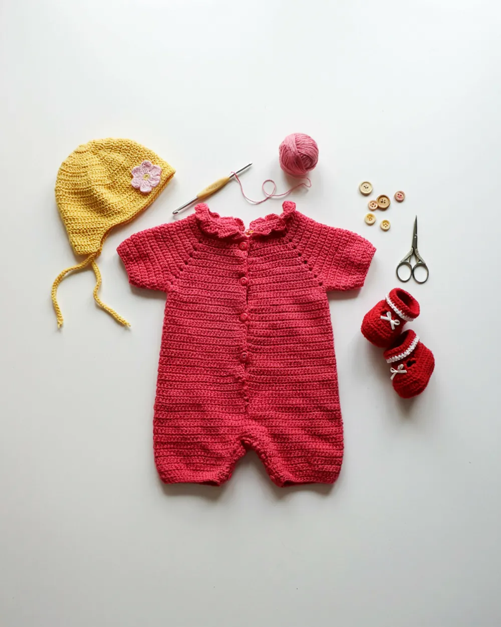 Bright handmade crochet baby set with romper, bonnet, and booties in vivid pink, red, and yellow, MapleHookCrochet colorful baby pattern set