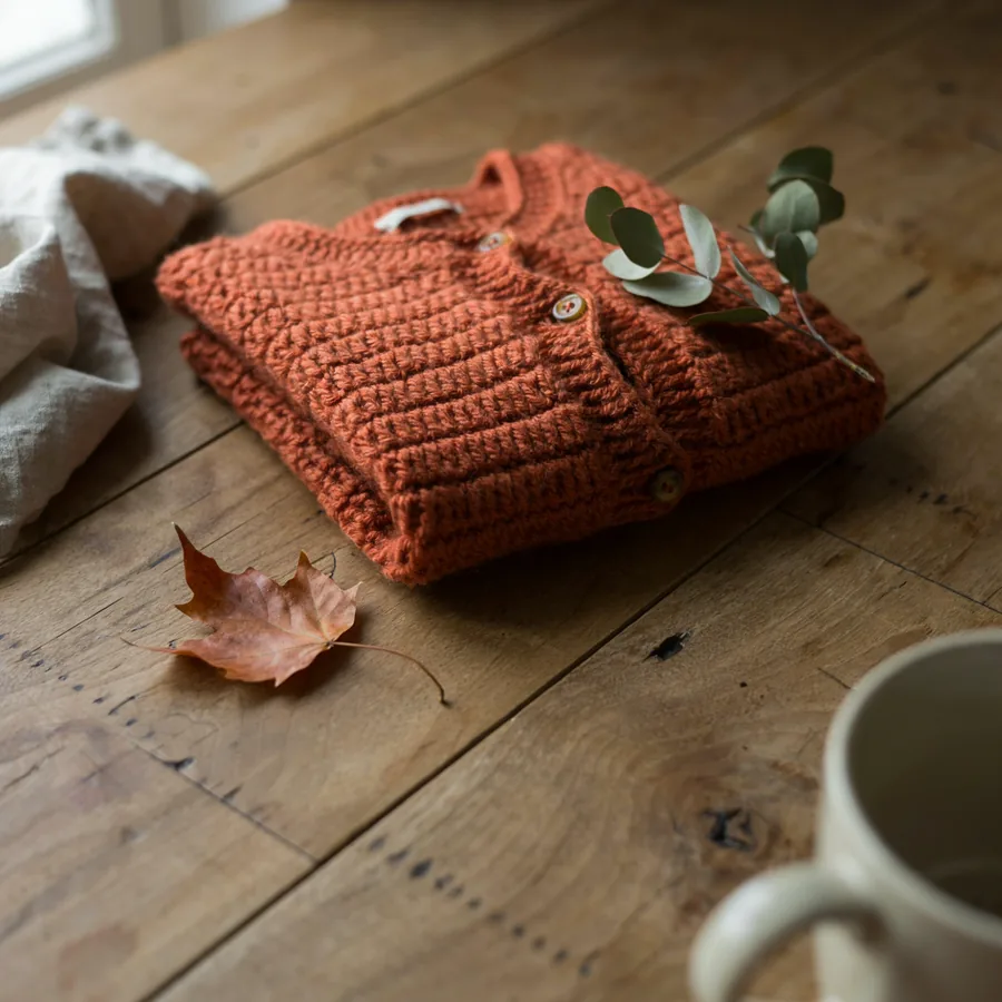 Handmade crochet cardigan sweater in warm terracotta color, neatly folded