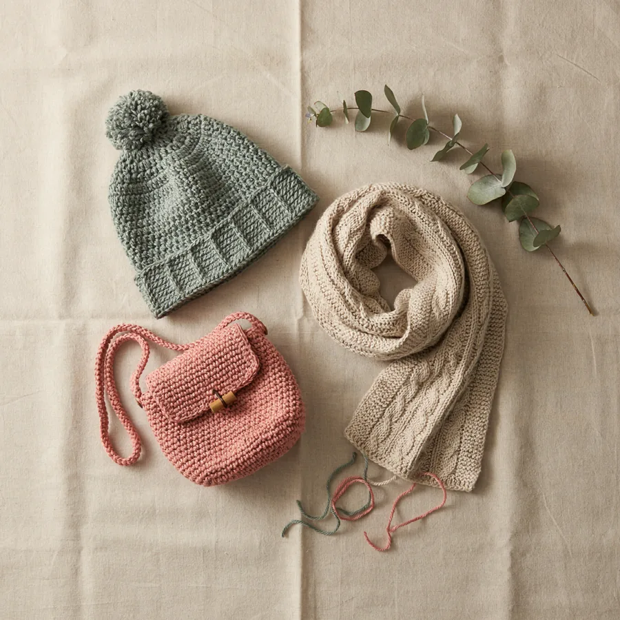 Handmade crochet accessories including a beanie hat, scarf, and crossbody bag