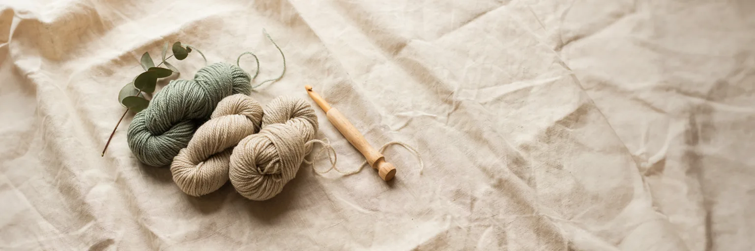 Pastel sage green wool yarn and wooden crochet hook flat lay, representing MapleHookCrochet's Privacy Policy page